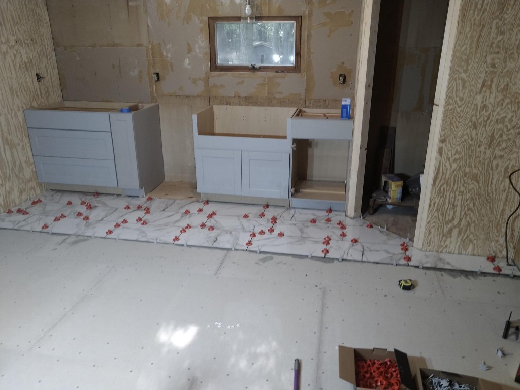 Floor tile installation along kitchen cabinets