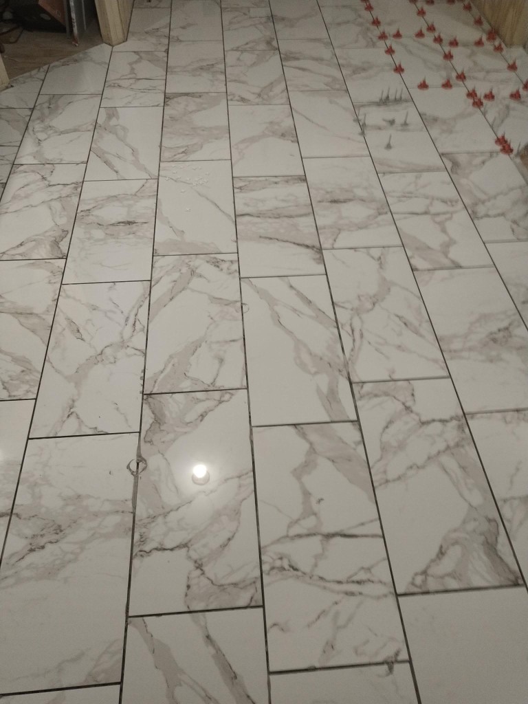 Close-up of marble-look floor tile with leveling spacers